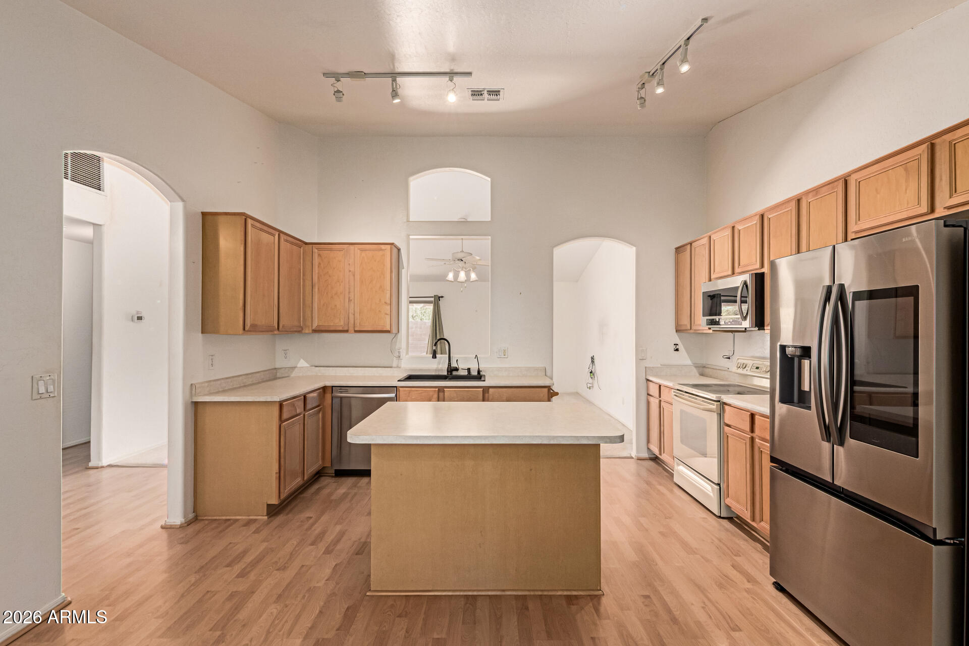 3123 South Del Rancho Mesa, AZ 85212 - Photo 4 of 15 a large kitchen with stainless steel appliances kitchen island granite countertop a stove a refrigerator a sink dishwasher and white cabinets with wooden floor