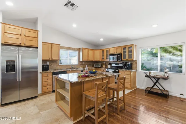 a view of a kitchen with kitchen island granite countertop lots of counter top and stainless steel appliances