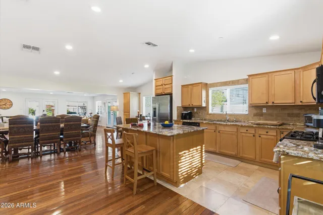 a kitchen with stainless steel appliances granite countertop a stove top oven a dining table and chairs with wooden floor