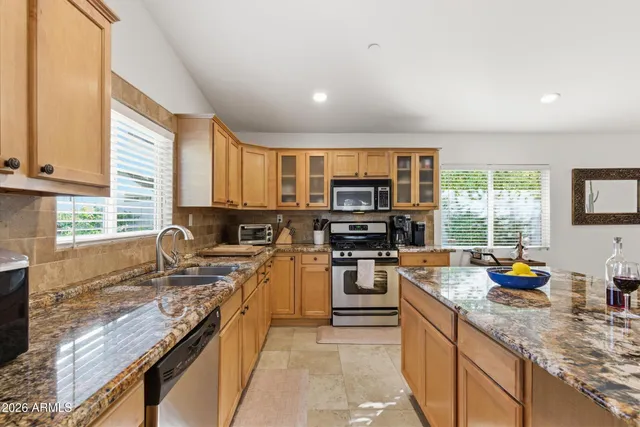 a kitchen with stainless steel appliances granite countertop a stove top oven a sink dishwasher a dining table and chairs with wooden floor