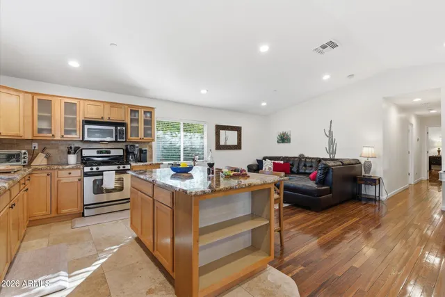 a kitchen with stainless steel appliances granite countertop a stove top oven a sink dishwasher a dining table and chairs with wooden floor