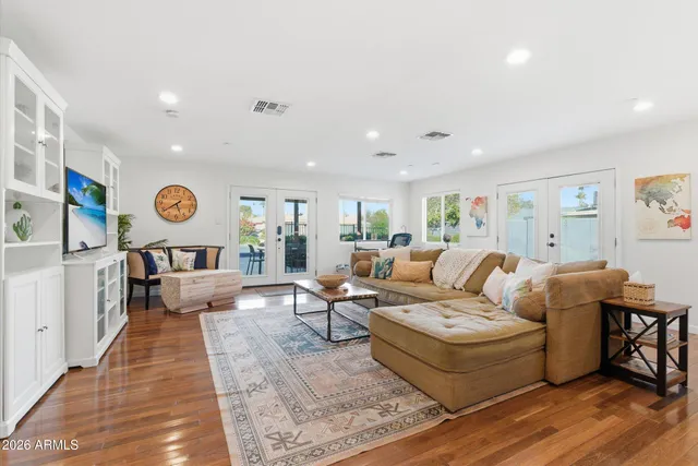 a living room with furniture kitchen view and a wooden floor