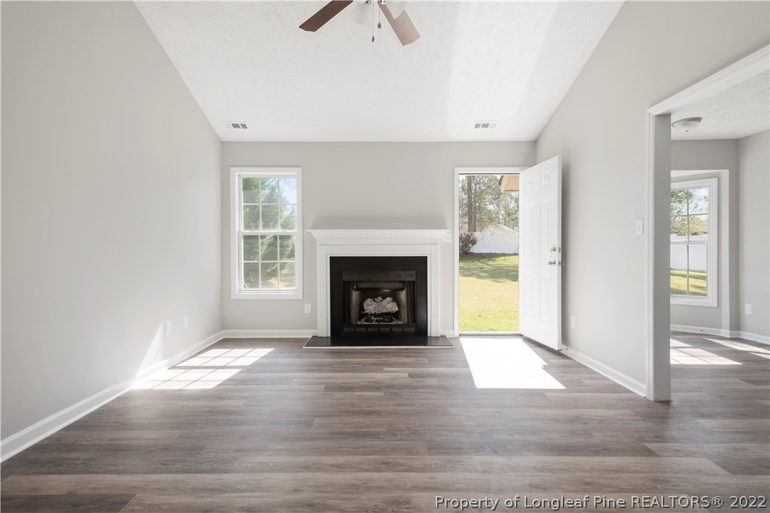 1150 Roundabout Road Cameron, NC 28326 - Photo 12 of 22 a view of an empty room with wooden floor fireplace and a window