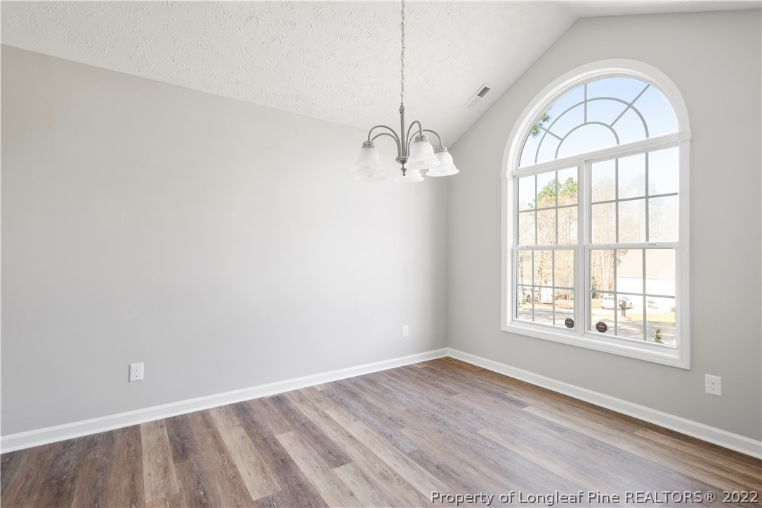 1150 Roundabout Road Cameron, NC 28326 - Photo 6 of 22 an empty room with wooden floor exposed radiator and windows