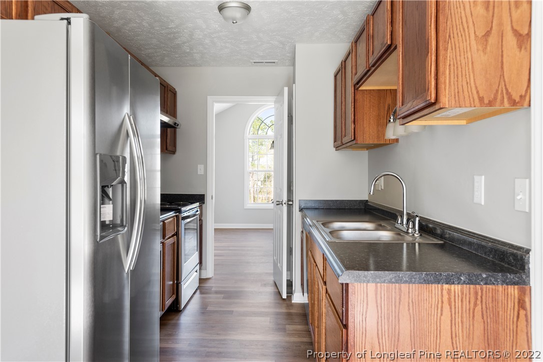 1150 Roundabout Road Cameron, NC 28326 - Photo 8 of 22 a kitchen with stainless steel appliances granite countertop a sink a refrigerator and wooden cabinets