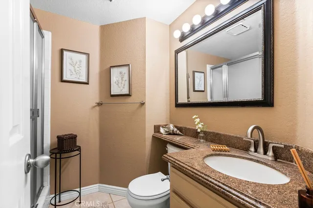 a bathroom with a granite countertop toilet sink and mirror