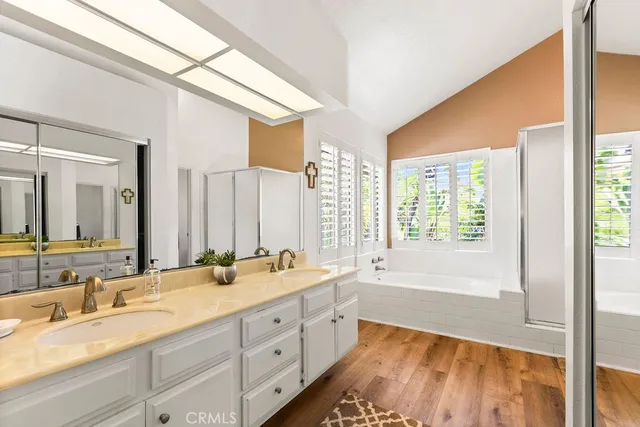 a spacious bathroom with a double vanity sink a large mirror and a bathtub