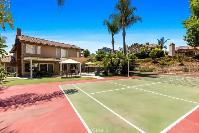 a view of tennis court with table and chairs under an umbrella