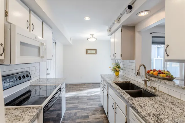 a kitchen with granite countertop a sink and a stove top oven with wooden floor