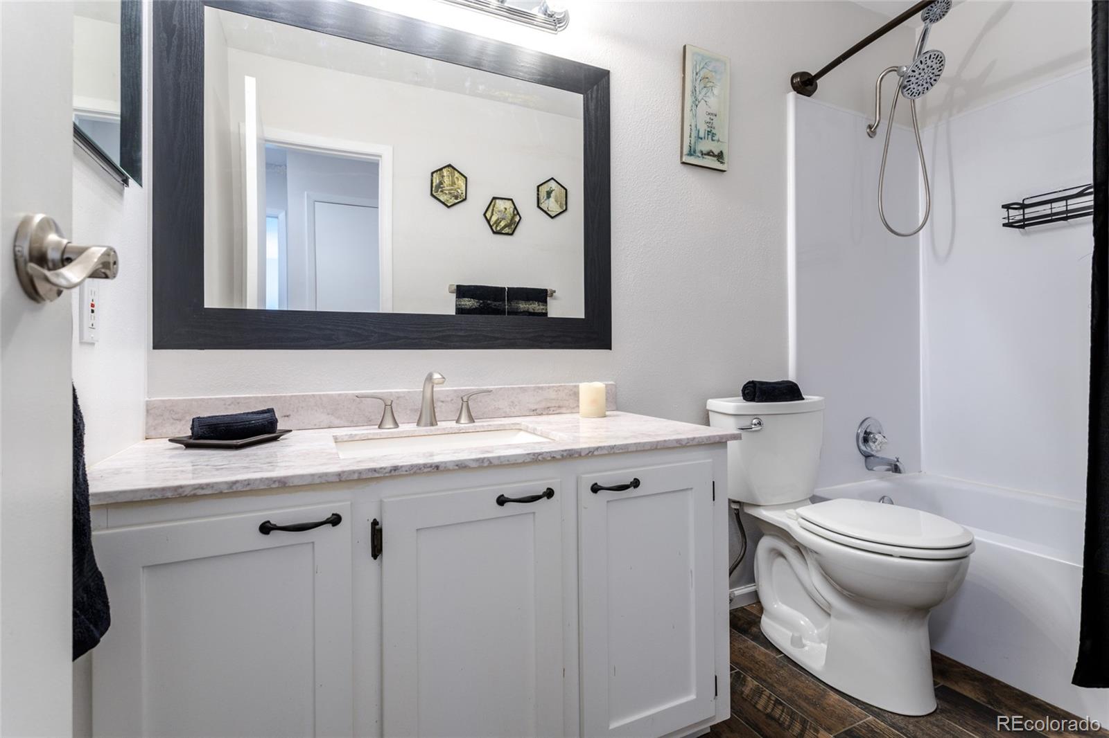 12143 Bannock Street, Unit B Denver, CO 80234 - Photo 22 of 32 a bathroom with a granite countertop sink toilet and mirror