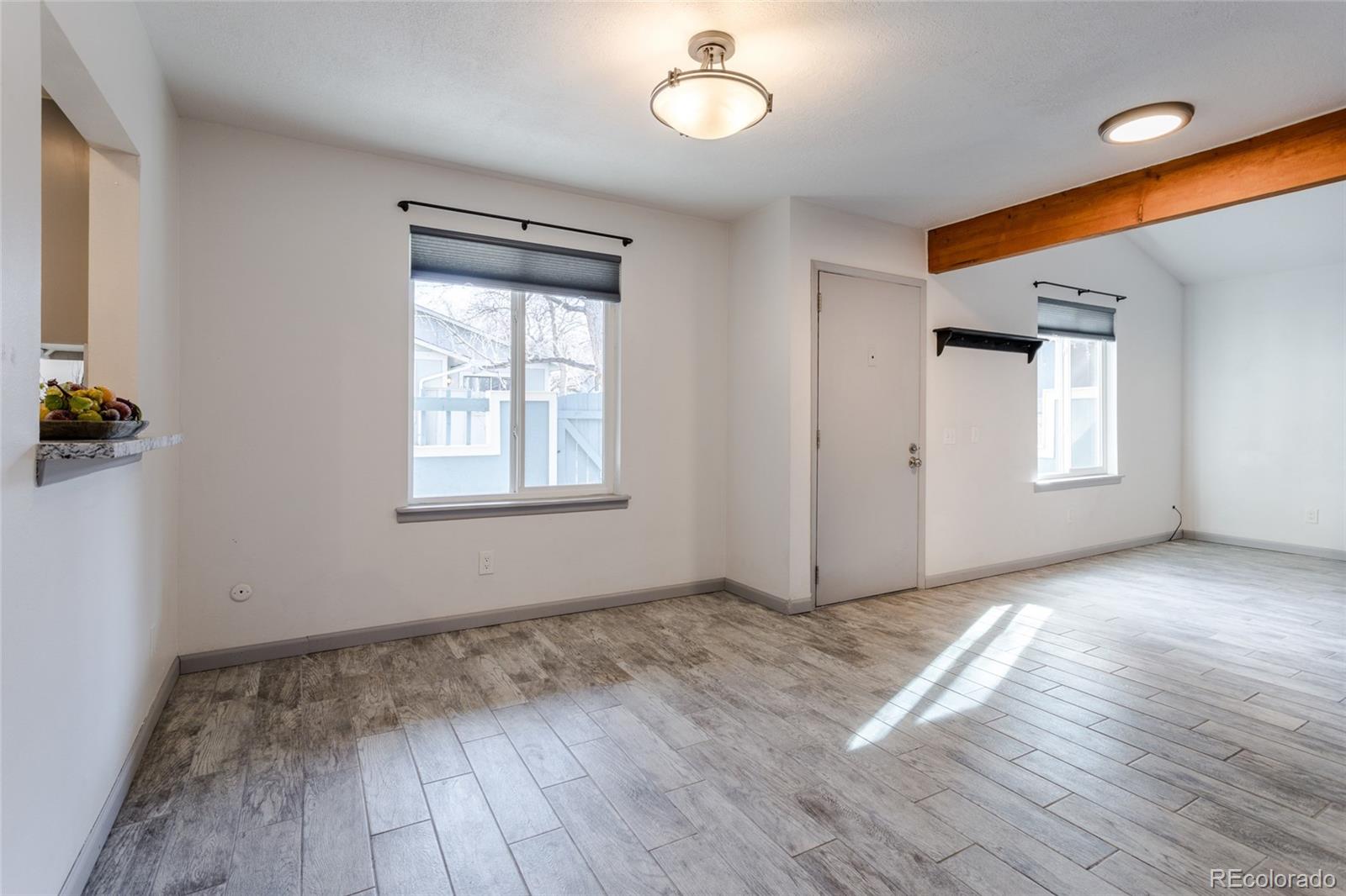 12143 Bannock Street, Unit B Denver, CO 80234 - Photo 10 of 32 an empty room with wooden floor chandelier and windows