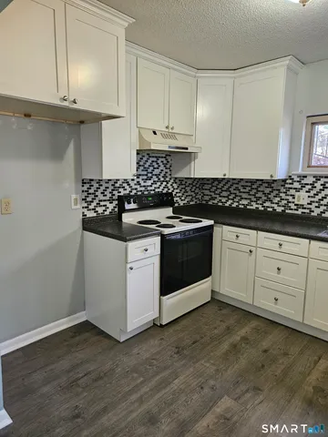 a kitchen with granite countertop white cabinets and white appliances