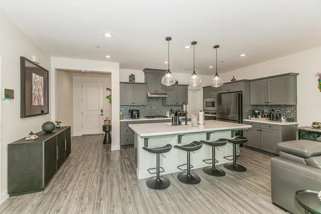 a large kitchen with stainless steel appliances a table chairs stove and cabinets