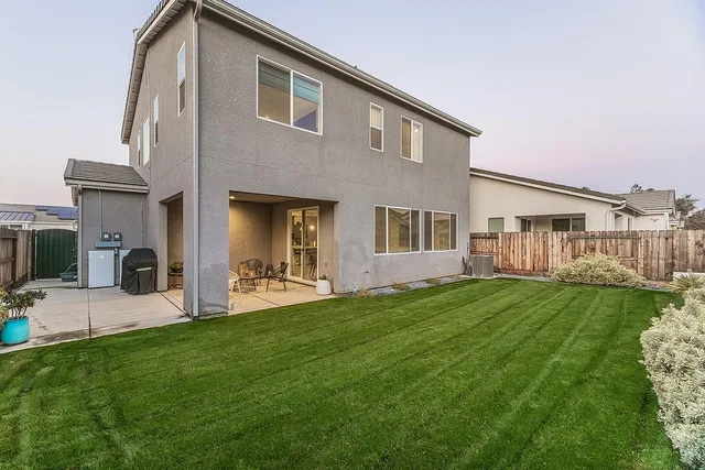a view of an house that has a big yard large trees and plants