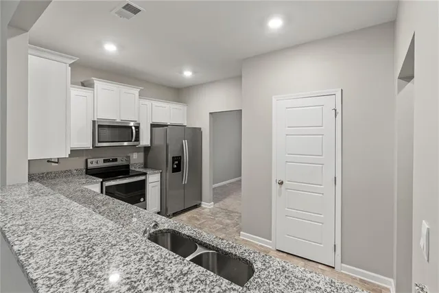 a kitchen with stainless steel appliances kitchen island granite countertop a refrigerator and a sink