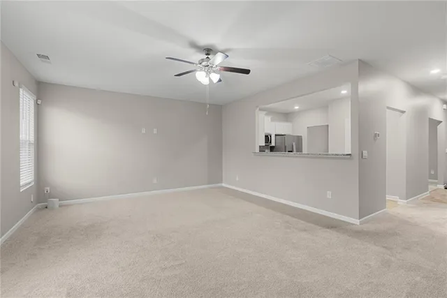 an empty room with a kitchen and a ceiling fan
