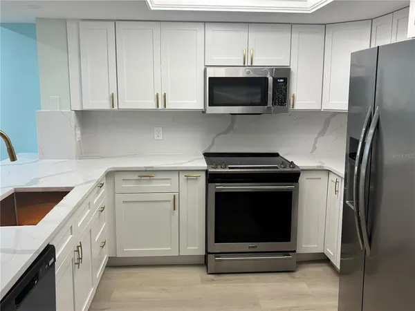 a kitchen with kitchen island white cabinets and stainless steel appliances