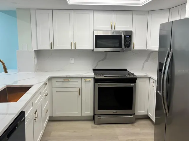a kitchen with kitchen island white cabinets and stainless steel appliances