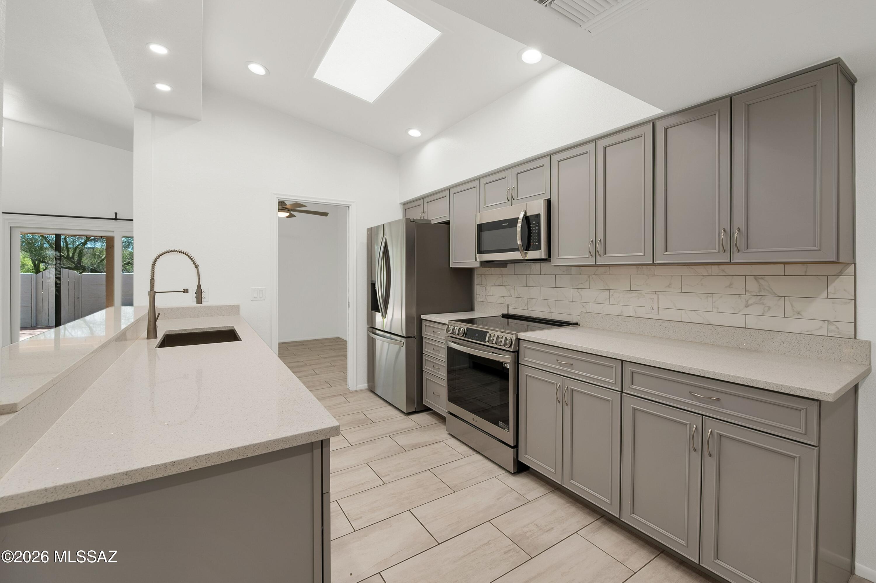 7408 East Wandering Road Tucson, AZ 85750 - Photo 12 of 25 a kitchen with stainless steel appliances a stove sink microwave and cabinets