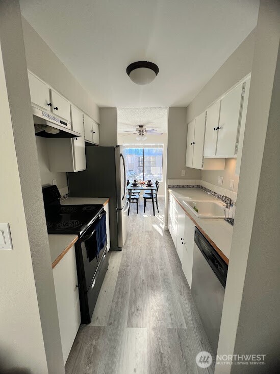 14510 124th Avenue Northeast, Unit B141 Kirkland, WA 98034 - Photo 6 of 17 a kitchen with granite countertop a stove top oven a sink dishwasher and a microwave