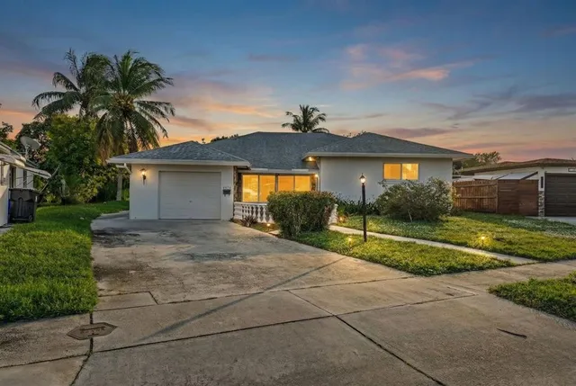 a view of house with a yard and palm trees