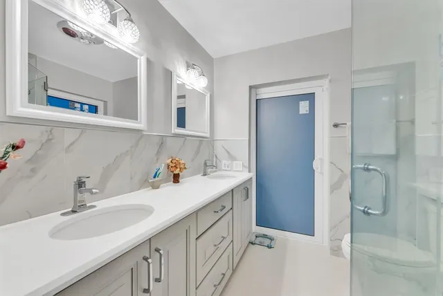 a bathroom with a double vanity sink mirror and shower