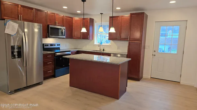 a kitchen with stainless steel appliances granite countertop a stove a refrigerator a sink and a oven