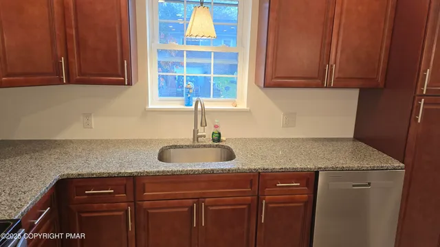 a sink with granite countertop cabinets and window