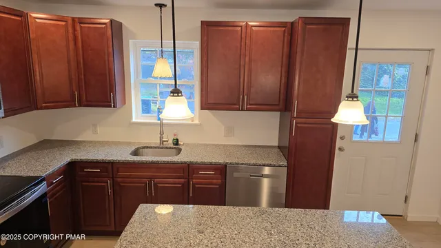 a kitchen with stainless steel appliances granite countertop wooden cabinets a refrigerator and a sink