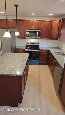 a kitchen with stainless steel appliances granite countertop a stove a sink and a refrigerator