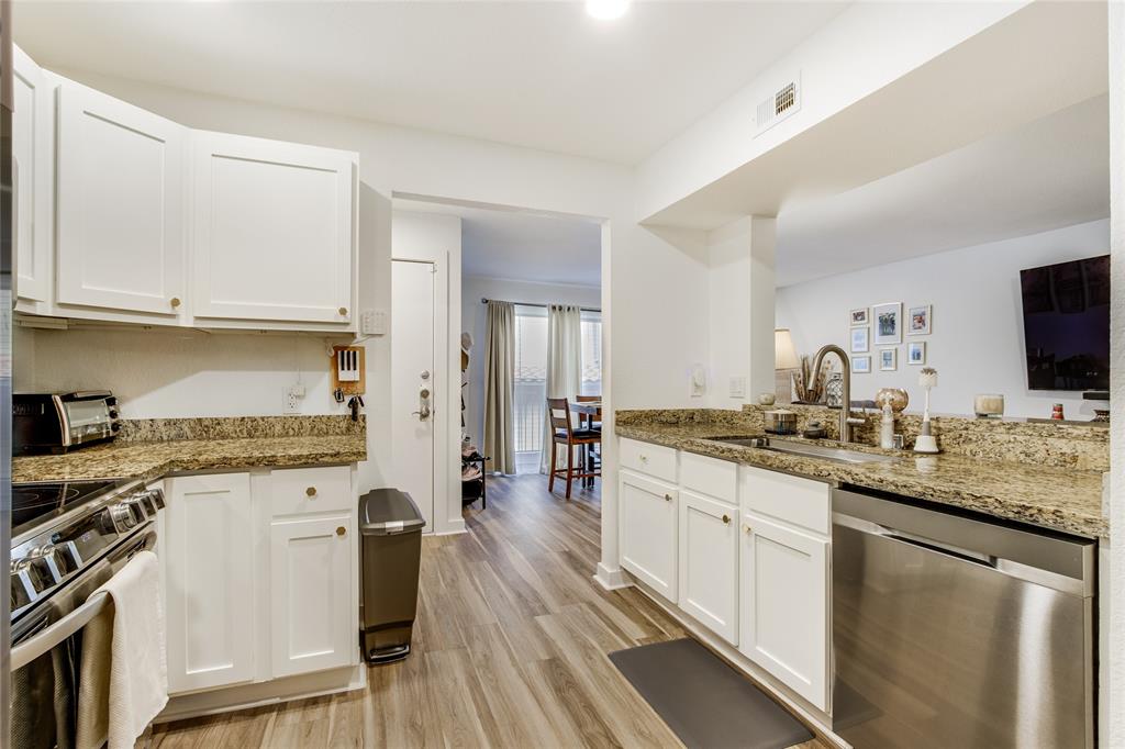 4777 Cedar Springs Road, Unit 7P Dallas, TX 75219 - Photo 11 of 28 a kitchen with stainless steel appliances granite countertop a stove top oven a sink dishwasher and white cabinets with wooden floor