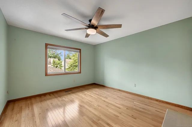 an empty room with wooden floor fan and windows