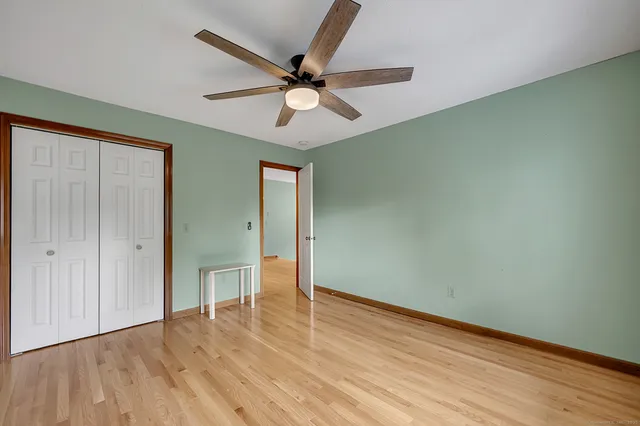 an empty room with wooden floor fan and windows