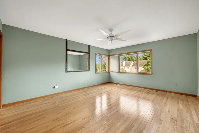 an empty room with wooden floor and windows