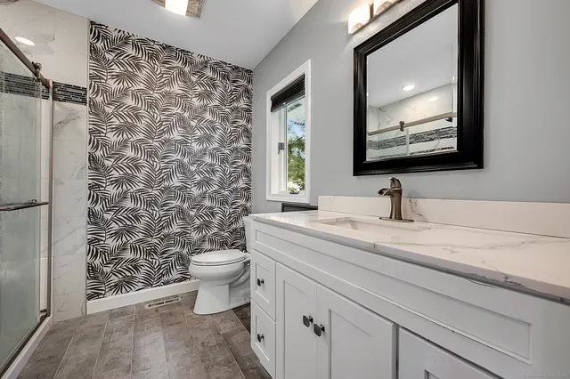 a bathroom with a granite countertop sink toilet and a mirror