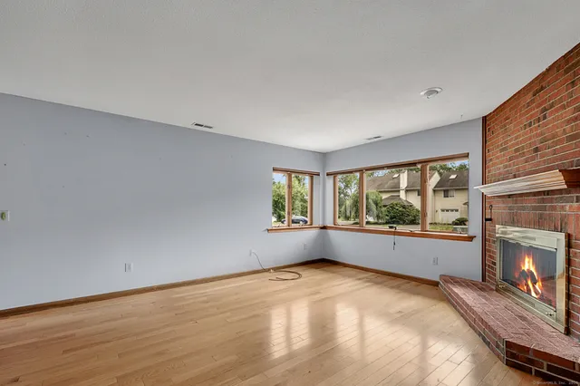 a view of empty room with wooden floor and fireplace