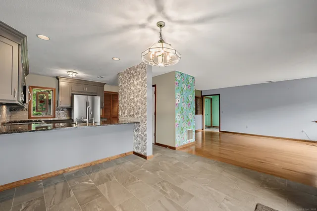 a view of a livingroom with a chandelier fan and kitchen view