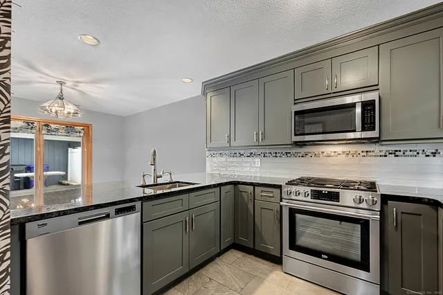 a kitchen with stainless steel appliances granite countertop a sink stove and microwave