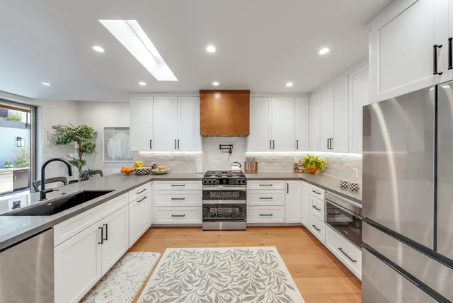 a kitchen with stainless steel appliances granite countertop refrigerator a sink and dishwasher a stove top oven with wooden floor