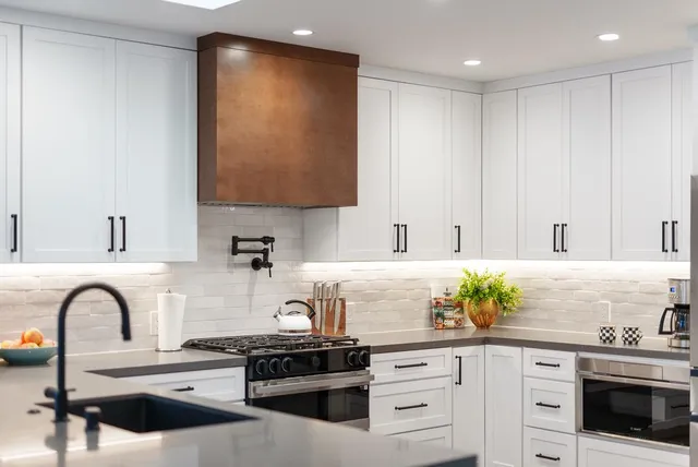 a kitchen with stainless steel appliances granite countertop a stove a sink and white cabinets