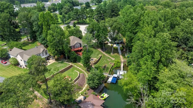 an aerial view of residential house with outdoor space and trees all around