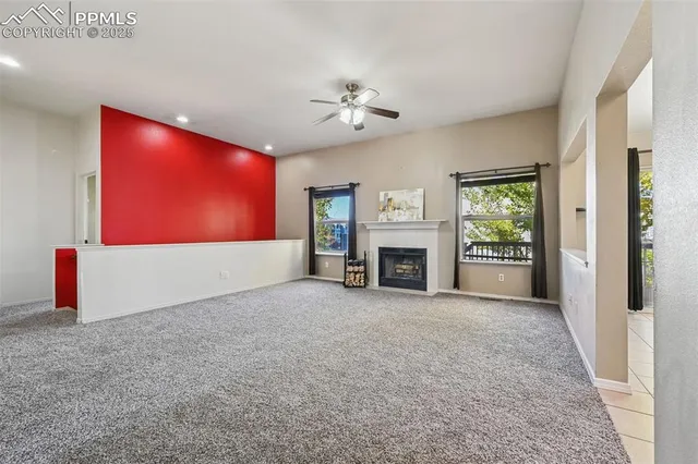 an empty room with windows fireplace and a chandelier fan