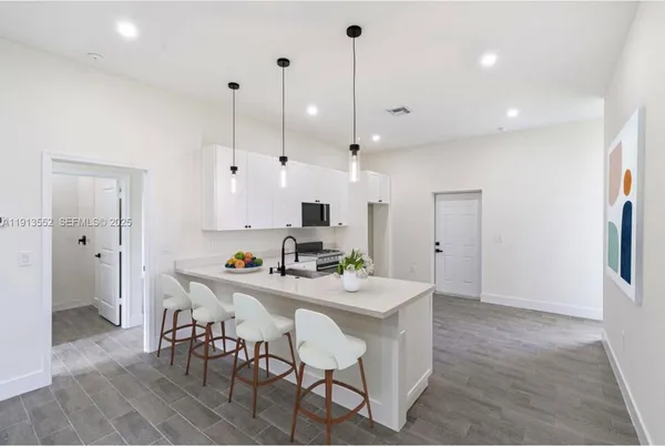 a kitchen with stainless steel appliances kitchen island granite countertop a table chairs and a refrigerator