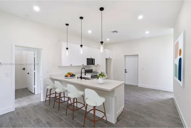 a kitchen with stainless steel appliances kitchen island granite countertop a table chairs and a refrigerator