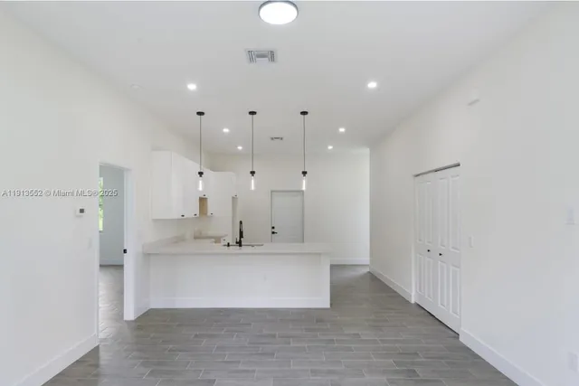a view of a kitchen with kitchen island a sink stainless steel appliances and cabinets