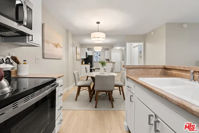 a kitchen with a kitchen island hardwood floor sink stove dining table and chairs