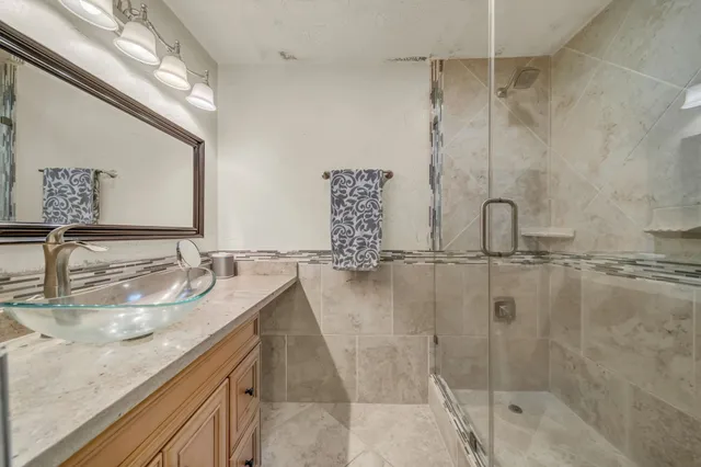 a bathroom with a granite countertop sink a mirror and shower