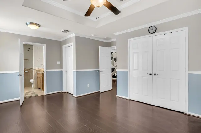 an empty room with wooden floor closet and windows