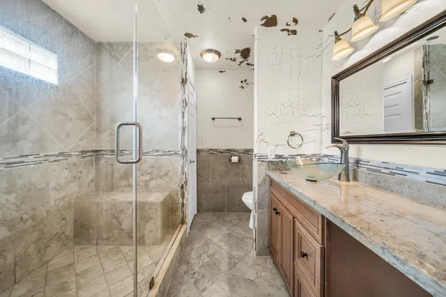 a bathroom with a granite countertop sink a mirror and a shower