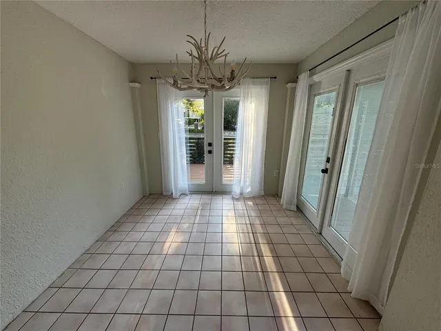 a view of empty room with window and chandelier